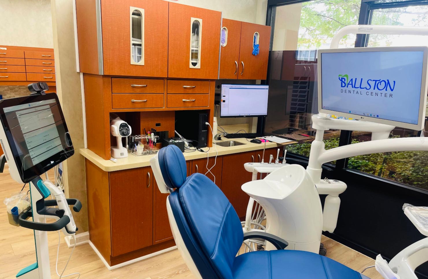 The image shows an interior view of a dental office with a reception area and a dental chair visible, featuring modern equipment and decor.