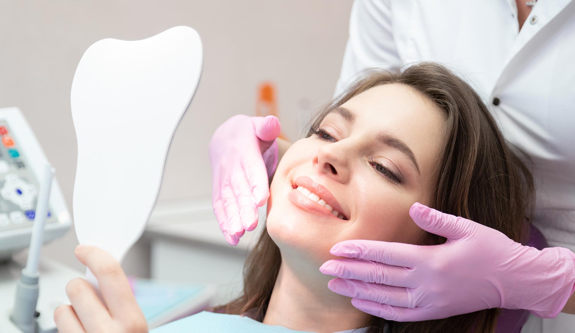 The image shows a woman sitting in a dental chair with a mirror on her face, receiving dental care from a professional who appears to be examining her teeth.