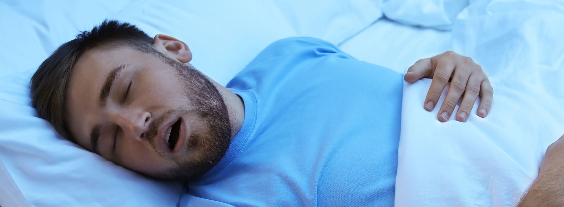 The image shows a man lying on his side in bed with his head resting on a pillow.