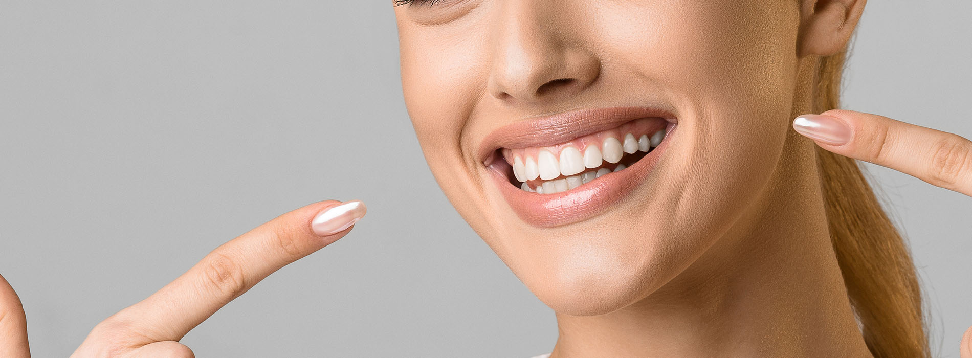The image shows a smiling woman with her hand touching her chin, against a white background.
