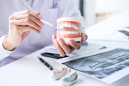 The image shows two pictures side by side on the left, a dental professional holding an open mouth model with a hand pointing at it, and on the right, a pair of hands holding a toothbrush over a photograph of a person s teeth.