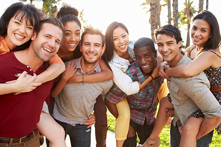 The image depicts a group of young adults posing together for a photo outdoors during the daytime.